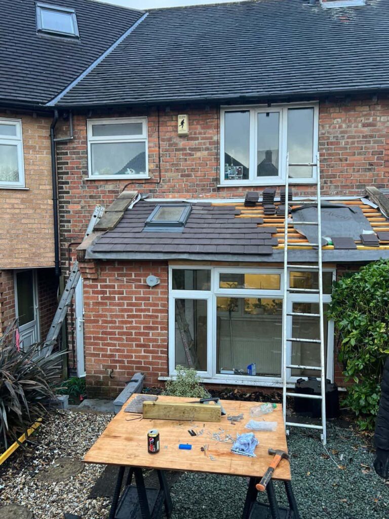 This is a photo of a roof extension that is having new roof tiles installed. This is a photo taken from the roof ridge looking down a tiled pitched roof on to a flat roof. Works carried out by MCM Roofing Repairs Salisbury